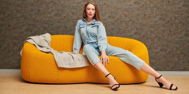 Frau-in-Jeans-Jumpsuit-auf-einer-Couch